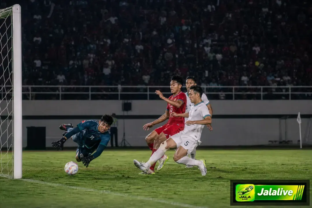 Momen pertandingan sepak bola Liga 1 Indonesia dengan pemain menyerang dan kiper melakukan penyelamatan